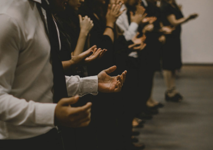 people in a row with hands up in prayer